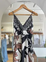 Vestido largo con estampado floral en tonos negro, blanco y marrón. Tiene breteles finos, escote en V y lazo ajustable en la cintura.