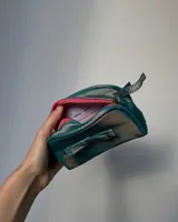 Neceser gris de tela satinada con cierre superior y detalle de moño en el frente.