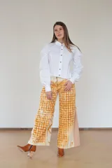 Pantalón de algodón color crudo con estampado de óxidos naturales en tonos marrones, de silueta amplia, tiro alto y diseño especial en los laterales.