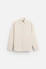 Camisa color crema de corte regular fit, confeccionada en tejido con viscosa. Tiene cuello solapa, manga larga con puños abotonados, bolsillo de parche en el pecho y cierre frontal con botones.