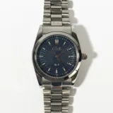Reloj plateado con correa de eslabones y esfera azul con diseño de ondas.