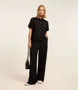 Conjunto de camisa de manga corta con botones y pantalón palazzo con cintura elástica y lazo, ambos en chiffon texturizado color negro con finas rayas verticales blancas.