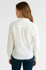 Camisa blanca de algodón con bordado calado, corte holgado, cuello camisero y cierre frontal con botones.