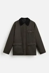 Parka relaxed fit color verde oscuro confeccionada en tejido de algodón con acabado encerado. Tiene cuello solapa combinado en pana negra, manga larga acabada en puño ajustable con botón a presión, bolsillos frontales de plastrón con solapa, bolsillo interior y cierre frontal de botonadura oculta por solapa.