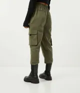 Pantalón jogger color verde militar, con cintura elástica ajustable con cinturón de hebilla plástica. Tiene bolsillos laterales tipo cargo con fuelle y puños elásticos.