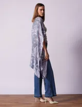 Kimono tejido con estampado abstracto en tonos grises y blancos, con mangas cortas y terminación de ruedo con borlas negras.