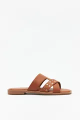 Sandalias bajas color marrón con tiras asimétricas y apliques de tachas doradas.