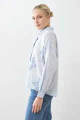 Camisa fucsia de manga larga con cuello camisero y cierre frontal con botones. Presenta apliques de estrellas bordadas en el frente y en el cuello.