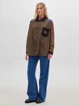 Camisa de corte suelto con estampado a cuadros color marrón y negro, con bolsillo frontal y escudo bordado en amarillo.
