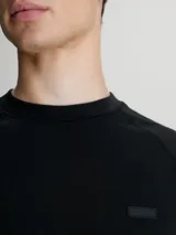 Buzo negro de algodón modal suave con cuello redondo, puños y bajo de canalé. Presenta un logo de Calvin Klein en la misma gama de tonos en el pecho.