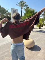 Remera color crema de corte holgado con estampado en rojo en la espalda con el texto "Ittaistars European Tour by Ittai Stars Company".