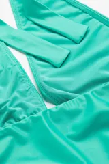 Traje de baño enterizo color verde agua, con escote halter y tiras para atar en la nuca que pueden cruzarse adelante.