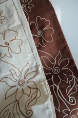 Pantalón slouchy tiro medio color beige con bordado floral marrón.
