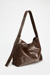 Bolso shopper marrón de efecto acharolado con asa de hombro ajustable, bolsillo interior con cremallera y cierre magnético.