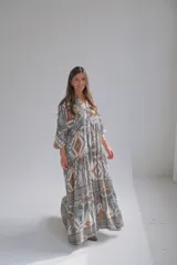 Vestido largo de corte amplio con estampado geométrico en tonos grises, marrones y blancos. Tiene cuello en V y mangas 3/4.