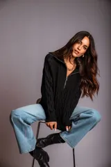 Buzo de punto color rosado, con cuello polo y cierre frontal parcial, de manga larga y diseño holgado.