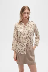 Camisa de viscosa con estampado floral en tonos azul, beige y blanco. Tiene cuello mao, mangas largas y bolsillos en el pecho.