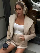 Conjunto color beige compuesto por chaqueta corta con cuello de piel sintética y short con cierre frontal.