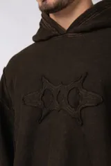 Buzo canguro negro con capucha, calce oversize, confeccionado en frisa 100% algodón con lavado gastado y aplique cosido en el pecho.