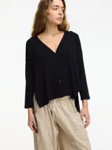 Cardigan negro de tejido con botones en la parte delantera y tajos verticales laterales.