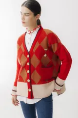 Cárdigan color beige con patrón de rombos en tonos marrones, cierre con botones, bolsillos frontales y bordados de cerezas.