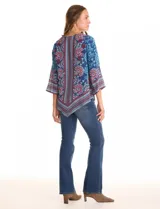 Blusa de gasa con estampado de arabescos y motivos florales en tonos azul marino, rojo y celeste. Presenta cuello redondo y mangas tres cuartos amplias. El bajo es asimétrico, más largo en los laterales.