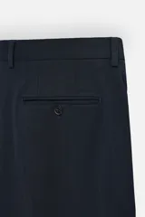 Pantalón de vestir azul marino, de corte slim fit, con bolsillos laterales y traseros. Se ajusta a la cintura con cinturón de cuero marrón.