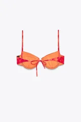 Top de bikini con estampado tie-dye en tonos rojo y naranja. Tiene aros, escote corazón, tirantes finos ajustables y cierre trasero con lazo.