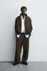 Pantalón jogger color verde oliva, corte relaxed fit, con cintura elástica ajustable con cordón, bolsillos laterales y detalle de bolsillo de vivo en la espalda. Presenta una banda lateral color crema a contraste.