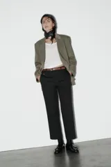 Pantalón de vestir color beige, de tiro alto y corte recto. Incluye cinturón marrón con hebilla metálica. Presenta bolsillos laterales y falsos bolsillos traseros de doble vivo. Cierre frontal con cremallera, botón interior y gancho oculto.