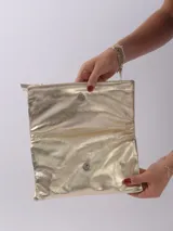 Sobre de mano color crema, con cierre de cremallera y tira de cuero para sujetar a la muñeca.