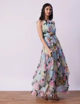 Vestido largo de gasa estampada con flores en tonos celeste, rosa y verde. Tiene cuello halter con abertura en forma de ojal, corte en la cintura con faja plisada y abertura central en la espalda con cierre invisible.