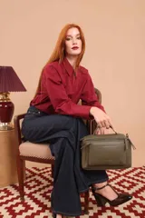 Bandolera verde militar de cuero sintético, con asa superior y correa larga ajustable. Cuenta con dos bolsillos frontales, uno de ellos con cierre cruzado.