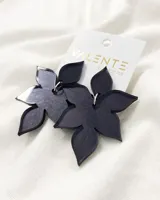 Par de caravanas colgantes con forma de flor de cinco pétalos, hechas de acrílico negro.