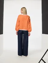 Suéter de punto jacquard color naranja con cuello redondo y ribetes en rosa.