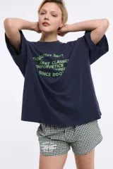 Remera blanca de algodón con cuello redondo y manga corta. Estampado pequeño de un ají rojo en el centro del pecho.