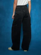 Pantalón de jean de tiro alto, color azul medio, con corte ancho y pierna recta. Presenta costuras marcadas en el centro de las piernas y bolsillos cargo a los lados.