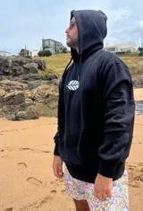 Hoodie negro de corte oversize con cordones ajustables y estampado frontal de una hoja blanca.