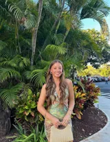 Vestido corto ajustado, color verde claro con estampado de hojas tropicales en tonos tierra. Diseño halter con escote profundo en V y aberturas laterales en la cintura.