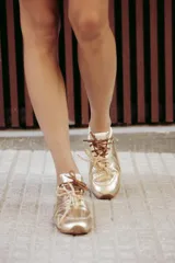 Zapatillas urbanas de cuero color tostado, con cordones verdes y suela de goma.