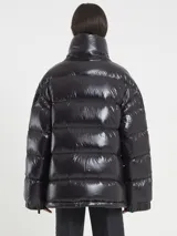 Campera puffer negra de acabado brillante, con cuello alto y cierre frontal. Presenta cierres funcionales en las mangas.