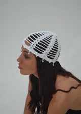 Gorro blanco de crochet con aberturas y detalles de cuentas colgantes.