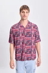 Camisa de manga corta con estampado de palmeras en tonos bordó y azul.