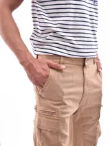 Bermuda cargo color beige, de largo hasta la rodilla, con bolsillos laterales tipo parche y cierre frontal.