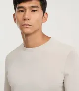 Suéter de manga larga y cuello redondo, color beige claro, de corte regular y tejido liso.