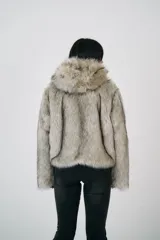 Chaqueta corta de pelo sintético color gris con capucha y cierre frontal con broches metálicos.