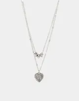 Collar multicadena plateado con dije de corazón calado y dije de cuentas cilíndricas.
