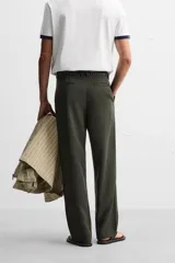 Pantalón verde oscuro de corte amplio confeccionado en tejido de lyocell. Presenta pliegues frontales, bolsillos laterales y traseros de ojal. Cierre frontal con cremallera y botón.