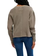 Buzo blanco de algodón con escote a la base, hombros caídos y mangas amplias con detalle de ojalillos y cordones en los puños.