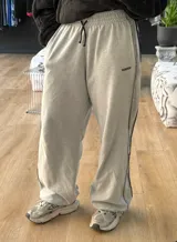 Pantalón de jogging gris con cordón ajustable en la cintura, corte holgado y puños elásticos.